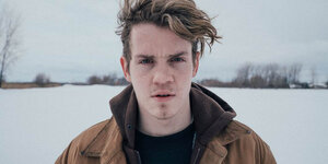 Ein junger Mann steht in einer verschneiten Landschaft
