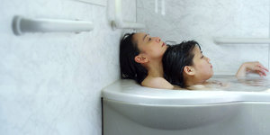 Mutter und Tochter liegen zusammen in der Badewanne