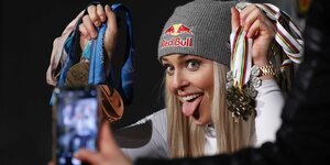 Lindsay Vonn posiert mit herausgestreckter Zunge und Händen voller Medaillen