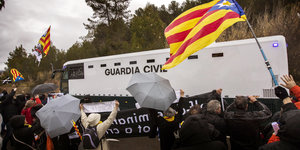 DemonstrantInnen schwenken katalanische Flaggen, als Angeklagten an ihnen vorbeigefahren werden