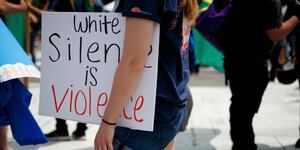 Eine Demonstrantin in Washington trägt ein Schild mit der Aufschrift "White Silcence is Violence".