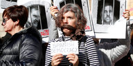 Bei einem Protest werden Fotos katalanischer Unabhängigkeitspolitiker gehalten und eine protestierende Frau hat ihren Mund überklebt