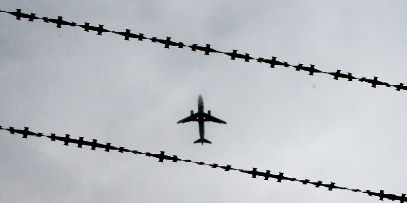 Ein Flugzeug, fotografiert durch einen Stacheldrahtzaun.