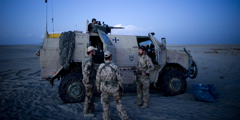 soldaten der bundeswehr stehen vor fahrzeug in der nacht