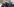 Drei Polizisten, einer von ihnen zielt mit einem Tränengasgewehr in Richtung Fotograf