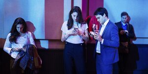 Junge Menschen in Business-Kleidung tippen auf dem Smartphone