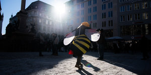 Eine Aktivistin in einem Bienenkostüm geht über den Marienplatz in München