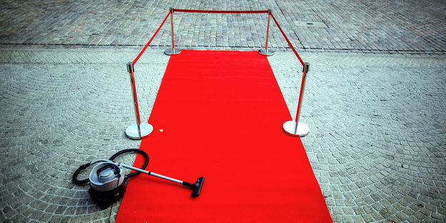 Ein roter Teppich mit Staubsauger