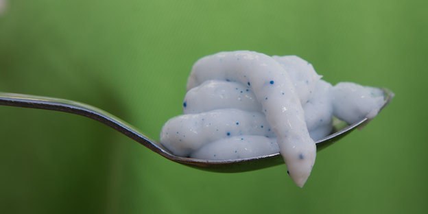 Ein Löffel mit einer Crème, in der Plastikkügelchen enthalten sind.