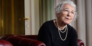 Die Kunderbuchautorin Judith Kerr sitzt auf einem roten Ledersofa