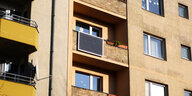 Blick auf ein Wohnhaus. An einem Balkon ist ein Solarmodul erkennbar