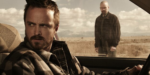 Szene aus "Breaking Bad": Jesse Pinkman sitzt am Steuer eines Autos im Hintergrund steht Walter White