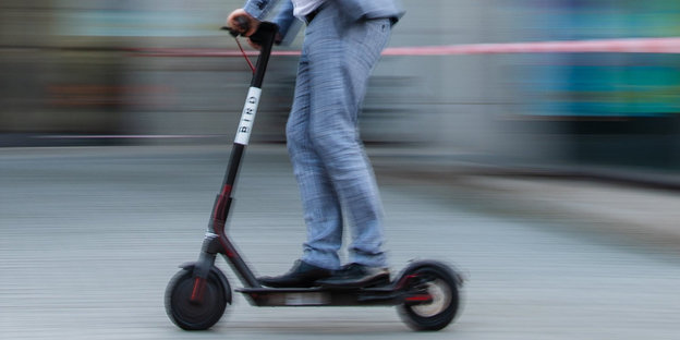 Ein Mann im Anzug auf einem e-Roller