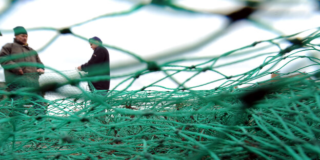 Zwei Fischer halten ein grünes Netz in ihren Händen.