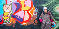 Anne Schmeckies steht vor einer mit Graffiti besprühten Wand.