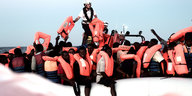 Menschen mit roten Rettungswesen auf einem Schlauchboot