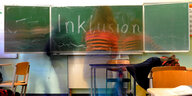 Das Wort "Inklusion" steht in einer Inklusions-Klasse auf der Tafel. Schüler gehen daran vorbei