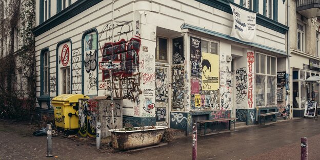 Ein Altbau, der mit Plakaten, Aufklebern und Graffiti versehen ist.