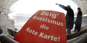 Eine rote Karte mit der Aufschrift "Zeig Rassismus die Rote Karte" liegt auf einem der Zuschauerplätze im Berliner Olympiastadion.