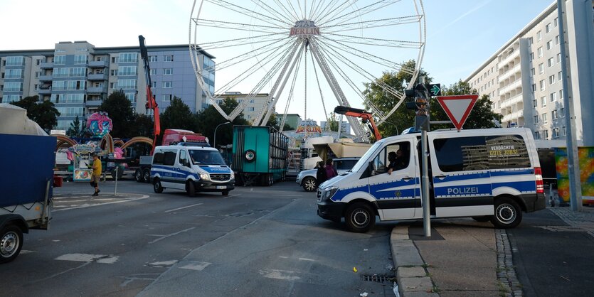 Zwei Mannschaftswagen der Polizei vor einem Riesenrad