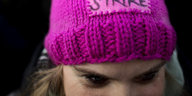 Frau mit pinker Mütze vor dunklem Hintergrund