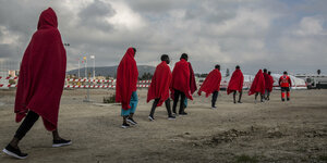 In rote Decken gehüllte, aus Seenot gerettete Flüchtlinge und Migrante sind in im Hafen Algeciras angekommen