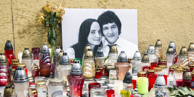 Viele Kerzen und ein schwart-weißes Foto von einer Frau und einem Mann