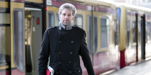 Ein Mantel tragender Mann mit kurzen Haaren und Drei-Tage-Bart steigt aus der Berliner S-Bahn