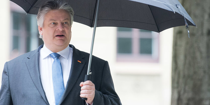 Thomas Seitz steht unter einem Baum mit Regenschirm in der Hand