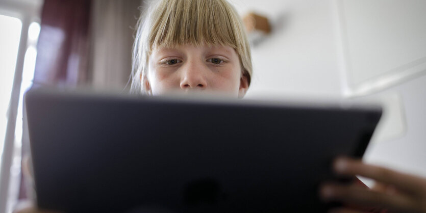 mädchen sitzt an einem tablet und spielt oder arbeitet damit