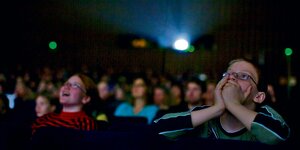 Schüler sitzen im Kino und schauen auf die Leinwand.