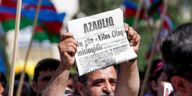 Ein Mann hält ein Exemplar der Zeitung Azadliq hoch. Demonstration für Pressefeiheit 2015 in Baku