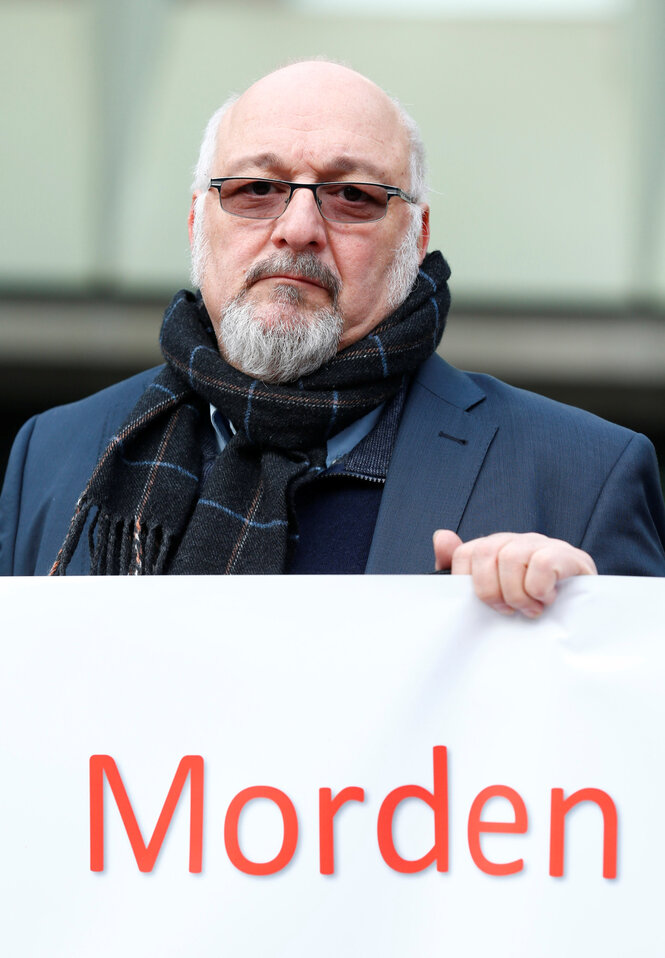 Ein Mann hält ein Plakat mitder Aufschrift "Morden"