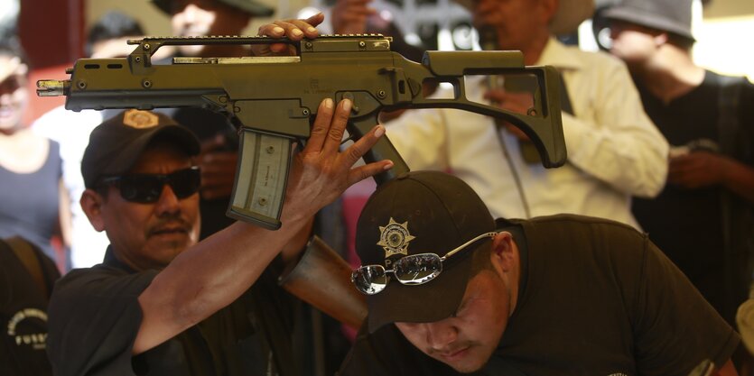 Mehrere Polizisten halten ein Maschinengewehr hoch