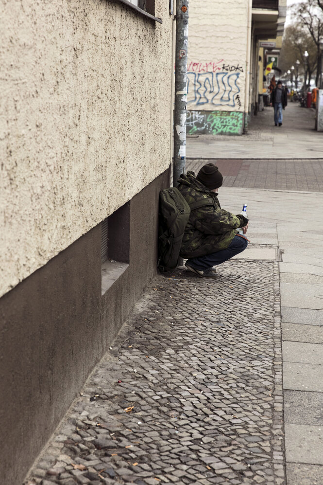 Ein Mann kauert an einer Hausfassade