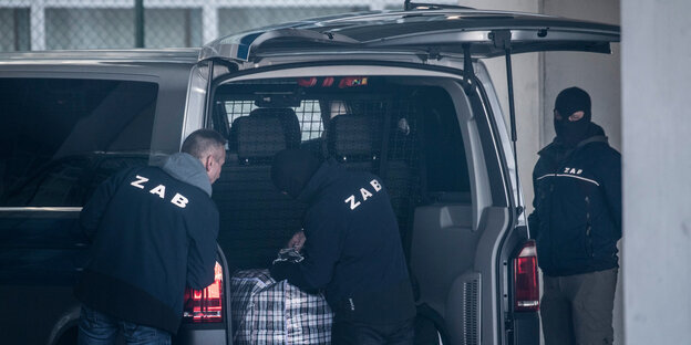 Drei Männer stehen am Kofferraum eines Transporters