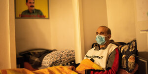 Mann liegt mit Atemschutzmaske in einem Bett