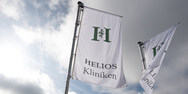 Zwei Fahnen mit Helios-Logo flattern im Wind.