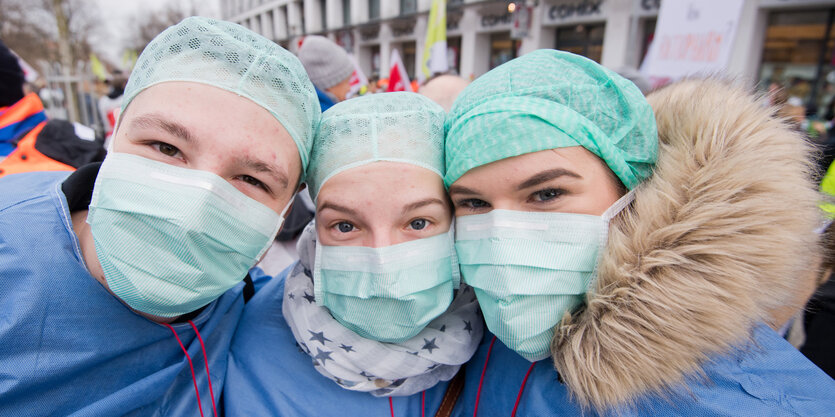 drei menschen mit op-mundschutz und op-kittel stehen im freien