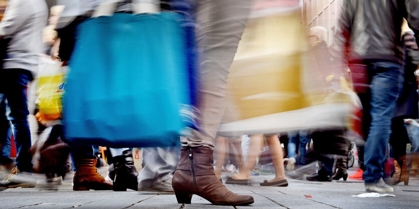 In einer Fußgängerzone sind viele Schuhe und Einkaufstaschen zu sehen