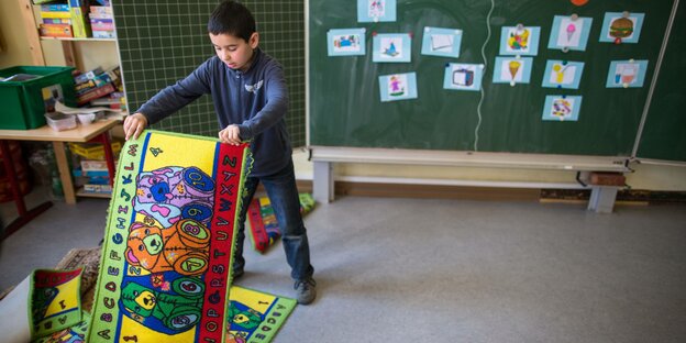 Ein Kind mit quietschbunten Gebetsteppichen in einem Klassenzimmer