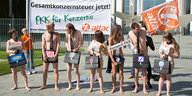 Sieben nackte ProtestierInnen verhüllen ihre Scham mit Schildern
