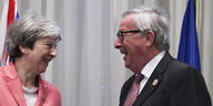 Theresa May und Jean-Claude Juncker stehen sich lachend gegenüber