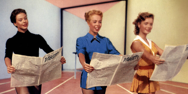 Bild von 1953: Drei Frauen stehen in einem Raum und haben eine Zeitung in der Hand