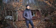 Ein Mann steht im Wald vor einer Hütte