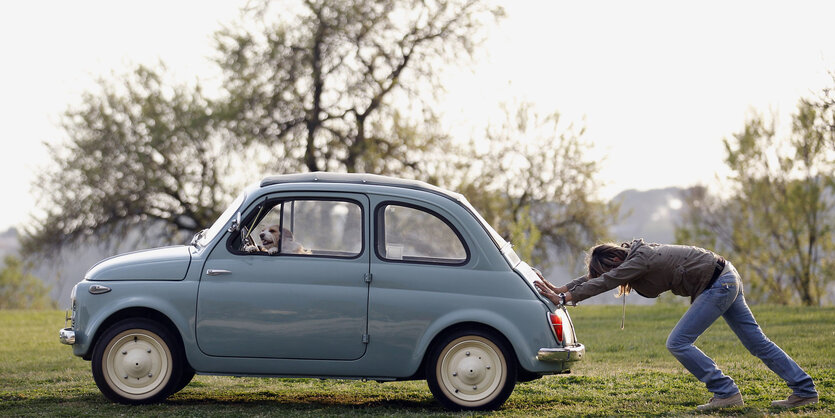 Eine Frau schiebt einen Fiat 500