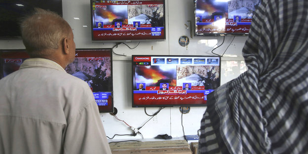 Pakistani schauen in einem Fernsehgeschäft die Nachrichten