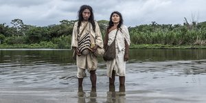 Ein Mann und eine Frau der Kogi stehen mit nackten Füßen im Fluß