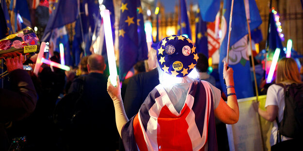 Auf einer Anti-Brexit-Demonstration hält eine Frau mit EU-Mütze einen großen leuchtenden Stab in der Hand