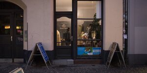 Ein Ladengeschäft von außen, ein Mann steht innen im beleuchteten Raum. Ein Ladengeschäft von außen, ein Mann steht innen im beleuchteten Raum.